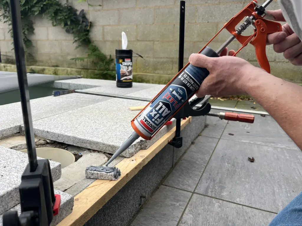 Applying a bead of Fix All Flexi beneath exterior stone paving